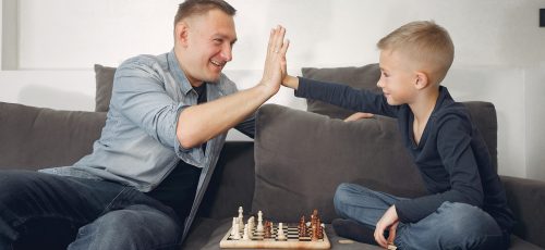 Father with little son. Family plaus in a chees. Peole at home.